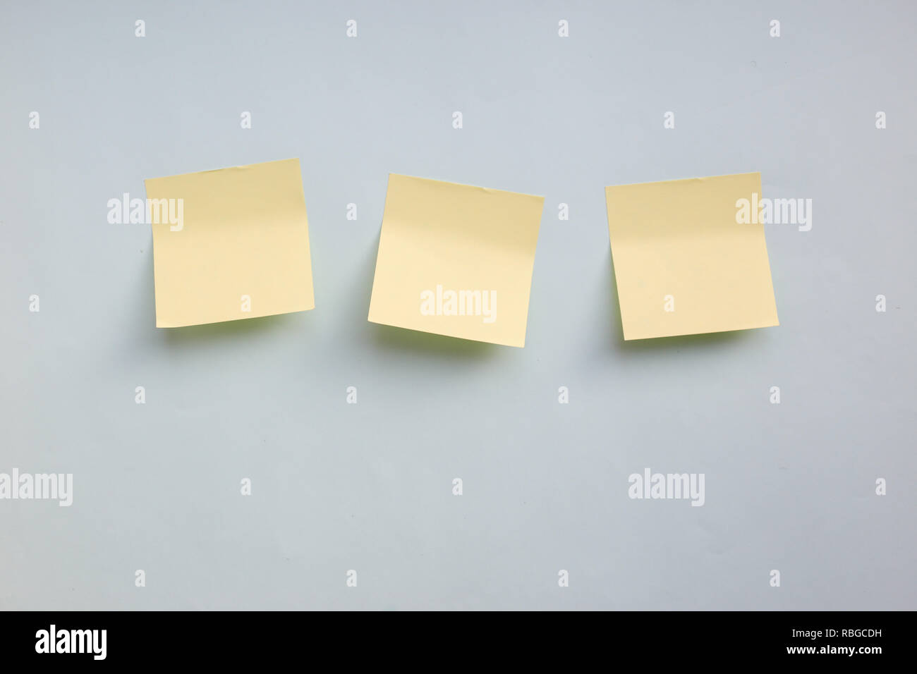 Three yellow paper stickers note with copy space on light blue background Stock Photo