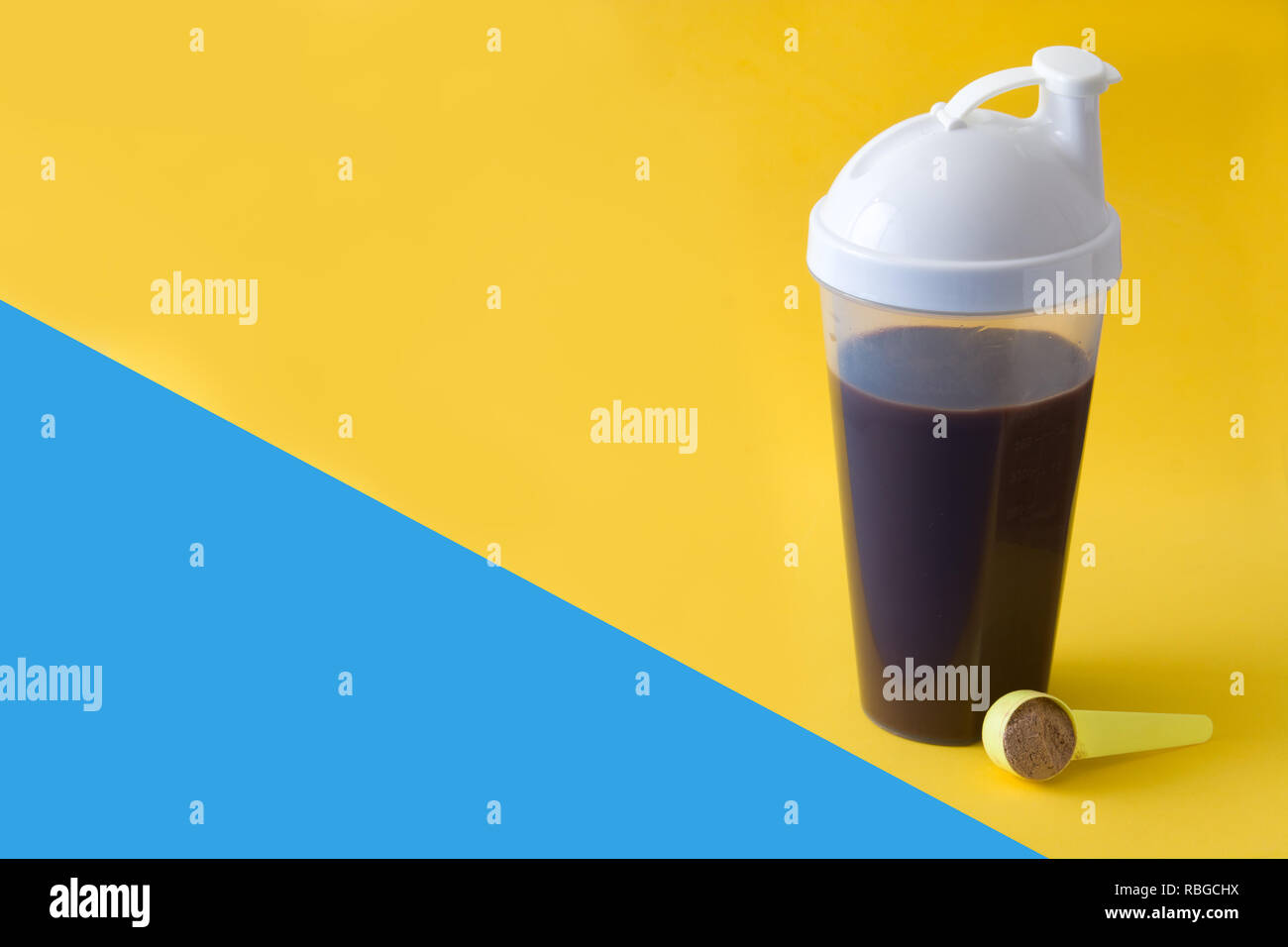 Chocolate protein shake on yellow and blue background. Copyspace Stock Photo