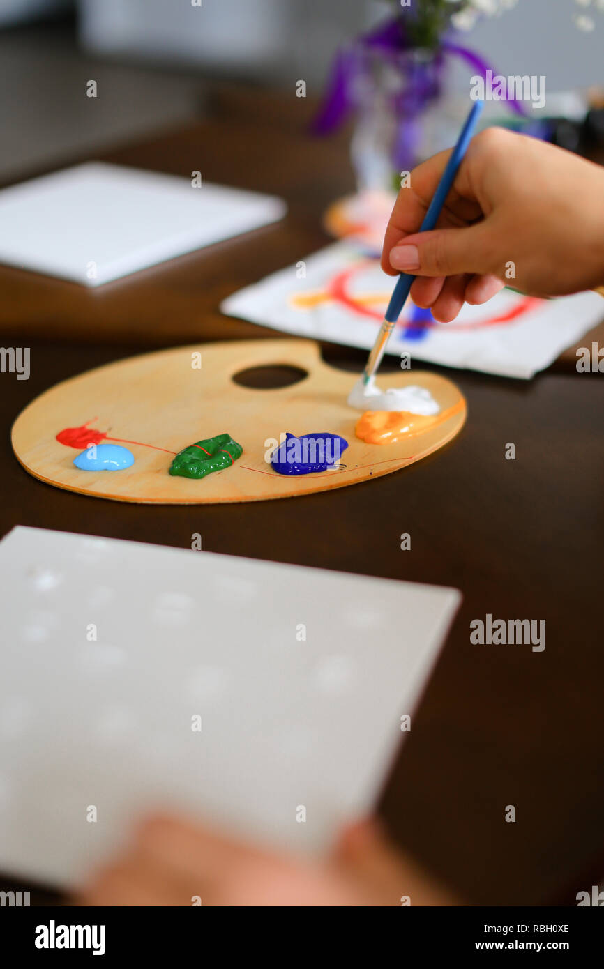 Close up colored palette with paints and brush in hand. Stock Photo