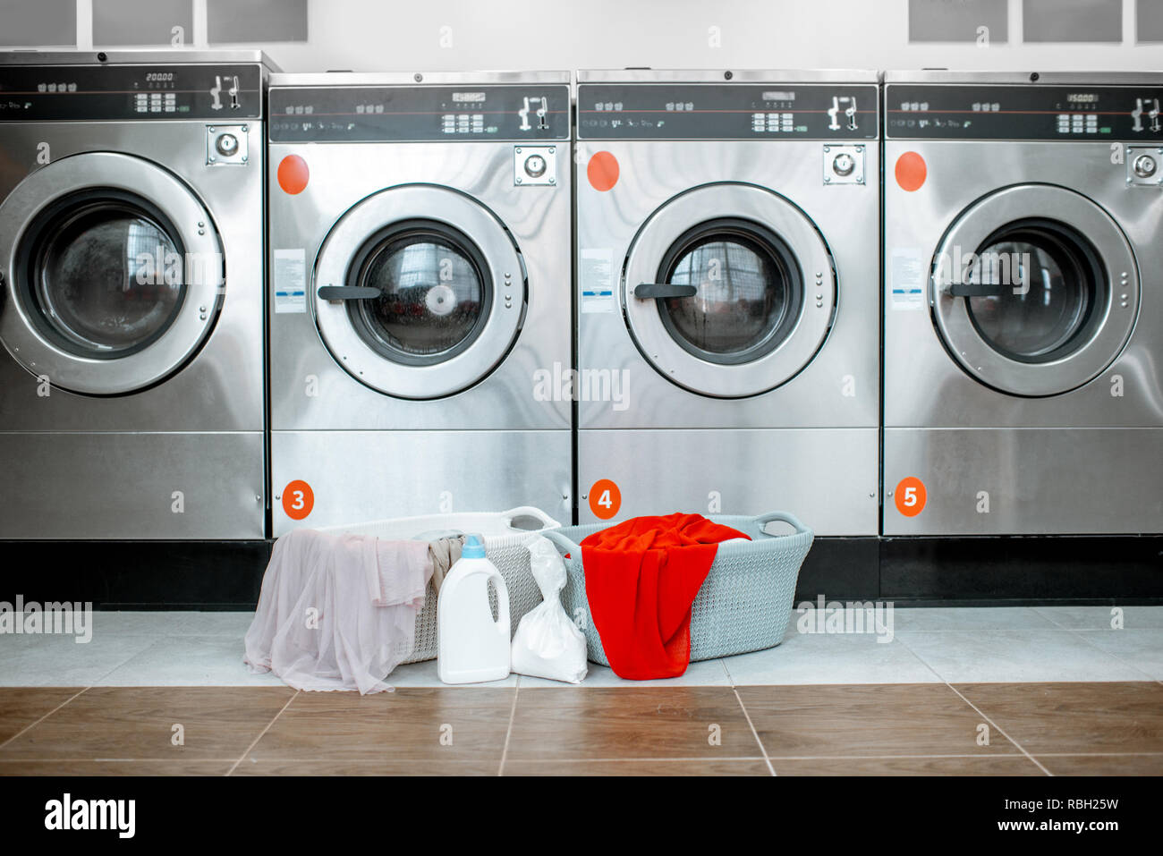 Professional washing machines with baskets full of clothes at the self-service laundry Stock Photo