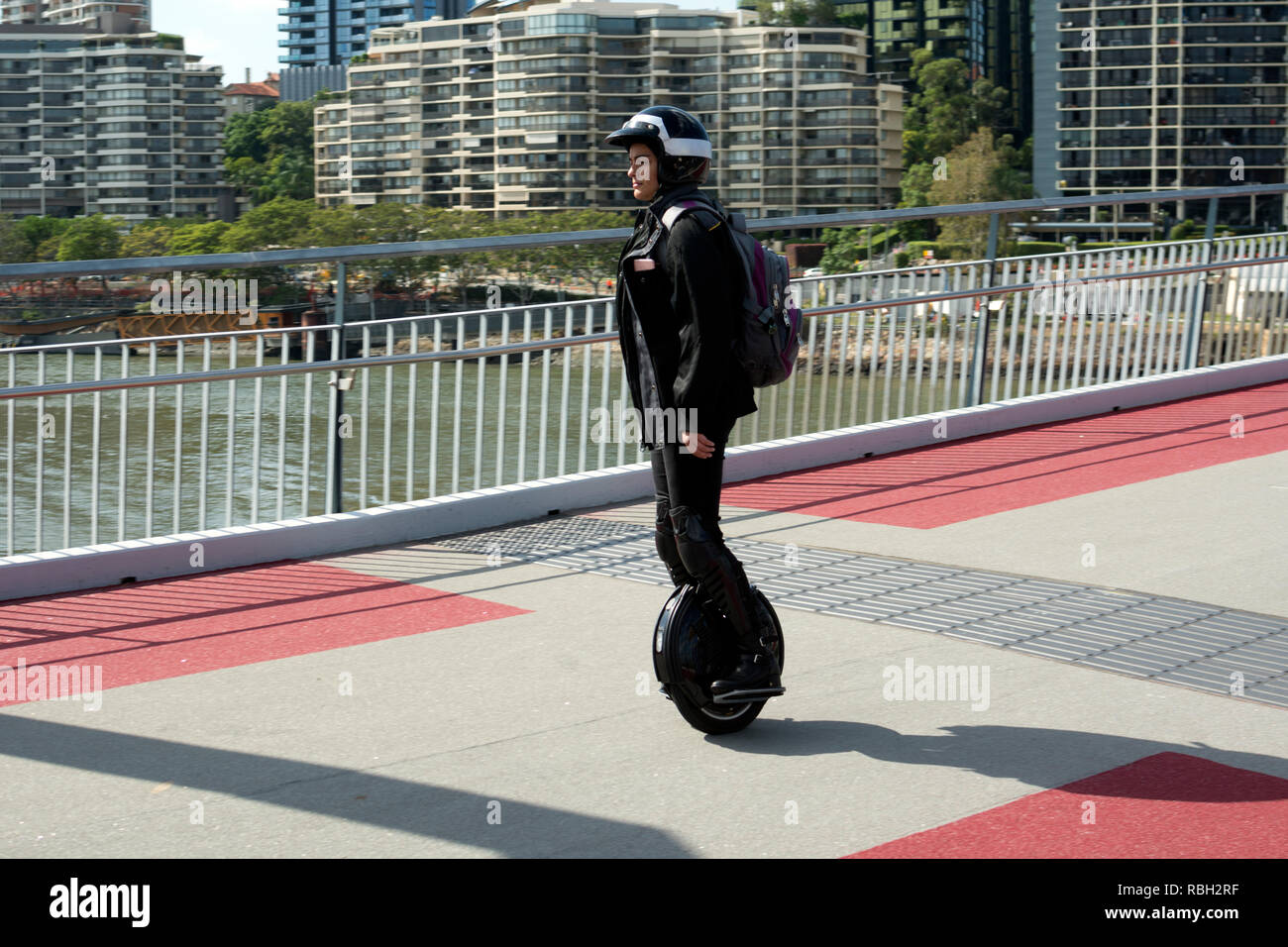A woman riding an electric unicycle across Goodwill Bridge, Brisbane
