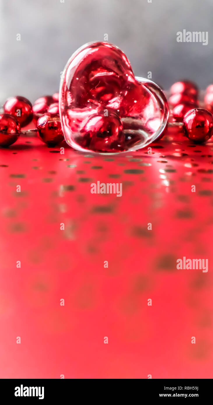 Shining transparent heart and a group of red beads. Perfect Valentine's Day  greeting card background. Vertical image in red tone on grey background  Stock Photo - Alamy