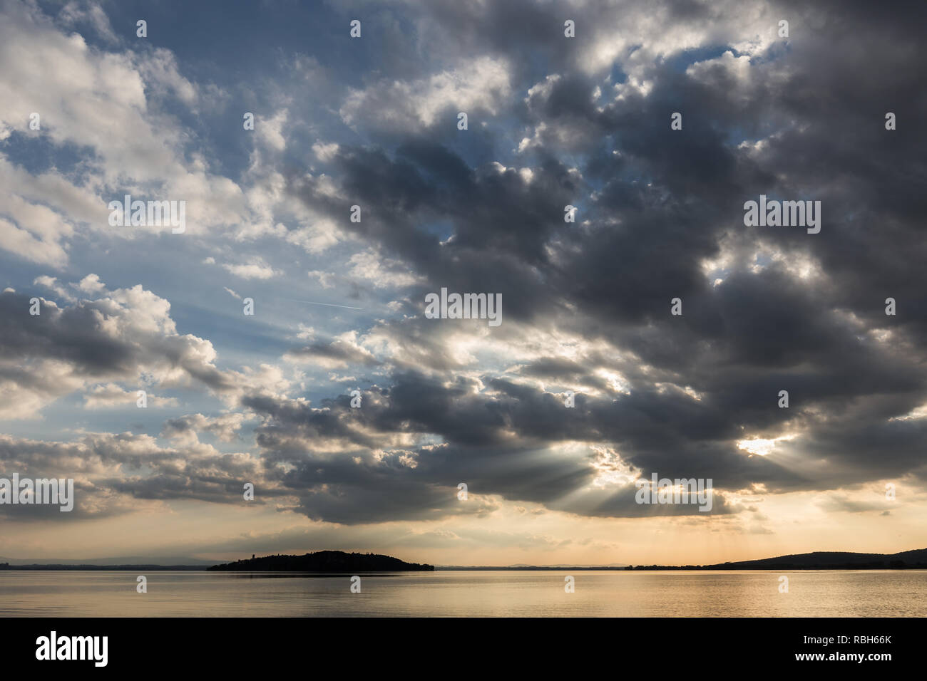 Beautiful wide angle view of a lake with an huge sky with clouds at sunset above an island Stock Photo