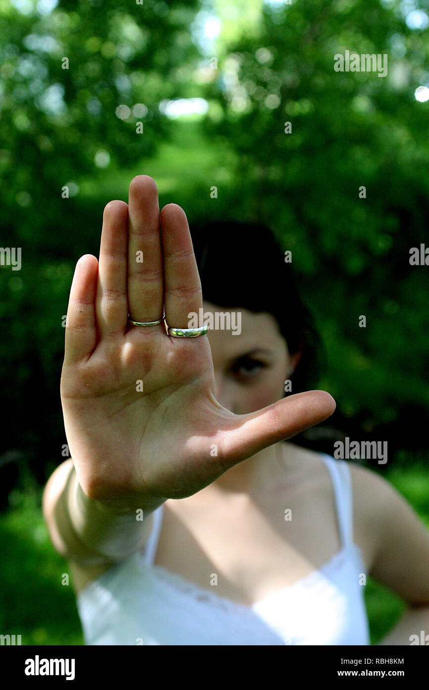 Brunette girl in a park outdoors on a sunny day giving hand signals Stock Photo