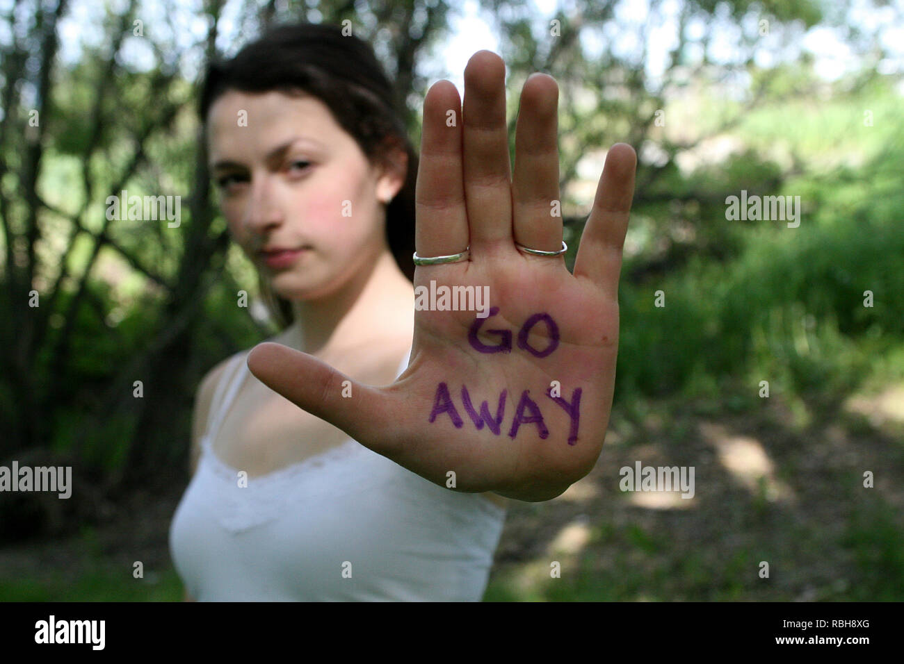 Brunette girl in a park outdoors on a sunny day giving hand signals Stock Photo