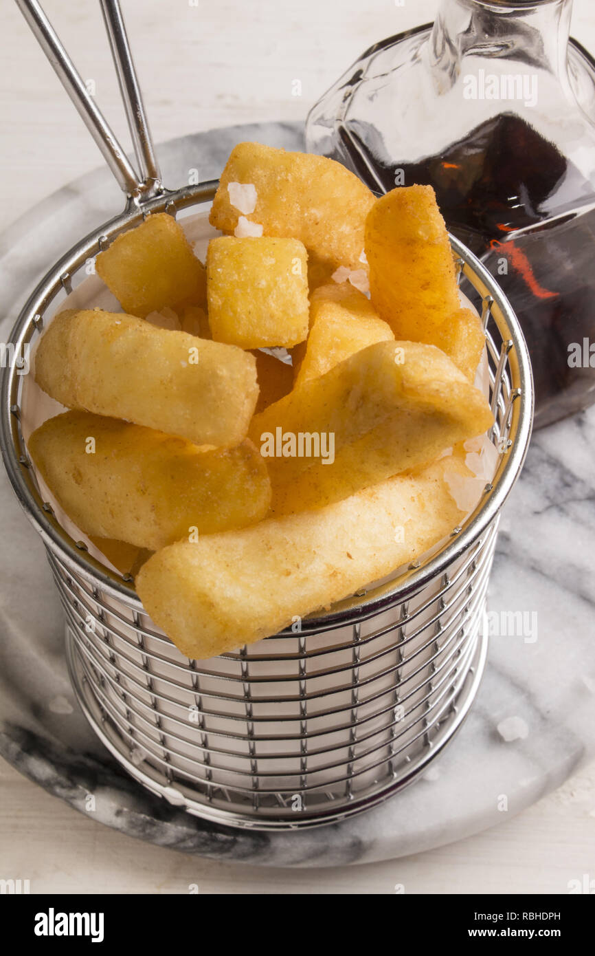 french fries in a serving basket, served with malt vinegar in a bottle