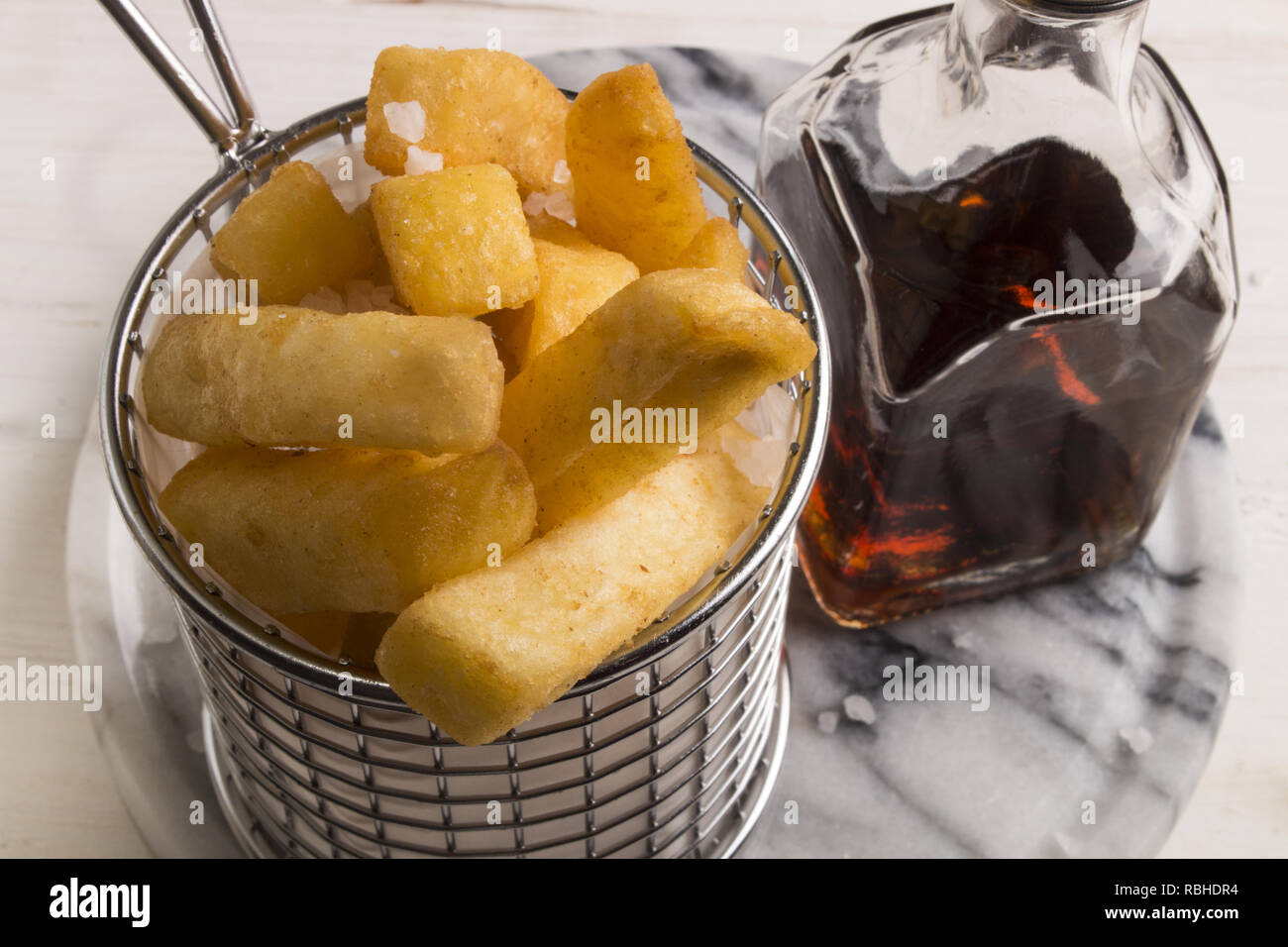 french fries in a serving basket, served with malt vinegar in a bottle