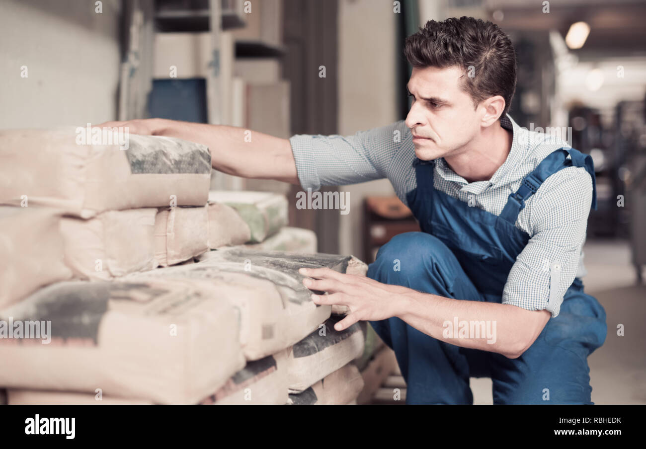 interested male in uniform is choosing cement in the building store room Stock Photo