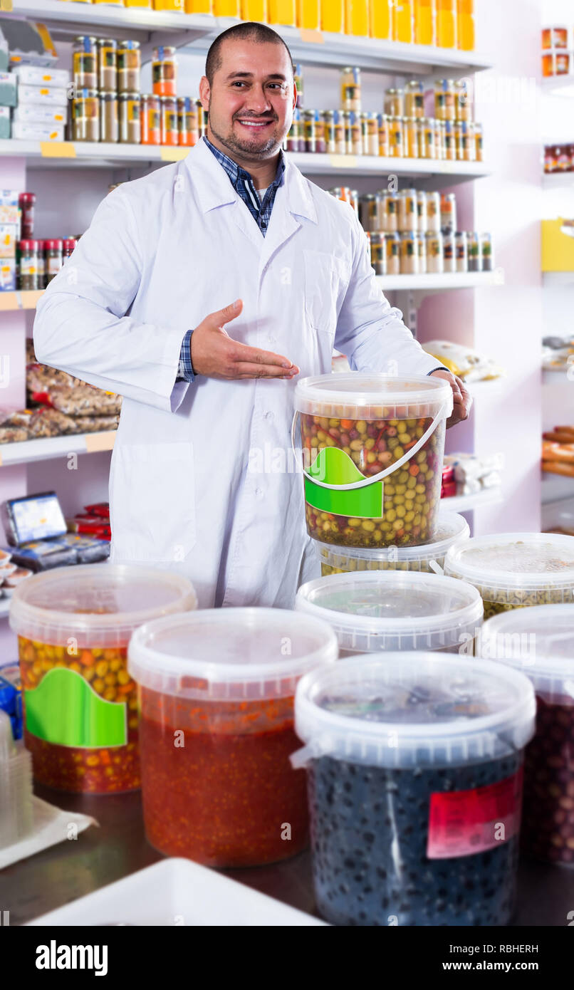 happy spanish shop staff standing near containers with olives in flavoured brine Stock Photo Alamy