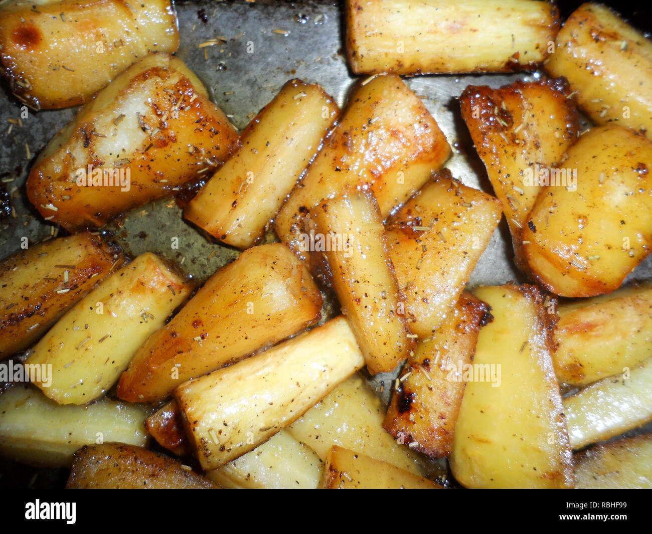 Honey roast Parsnips in the oven roasting tin. Stock Photo
