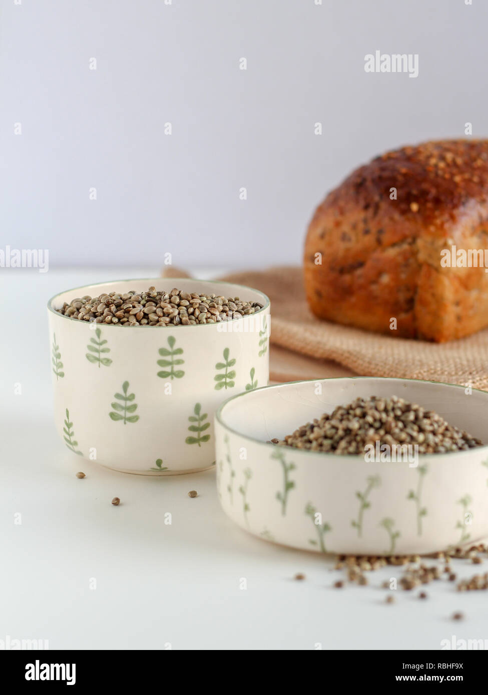 Organic hemp whole seeds in bowls and homemade bread on a white background Stock Photo