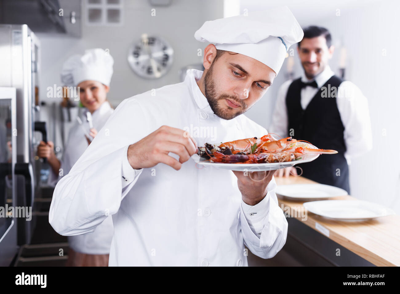 Head chef checking dishes in kitchen of fish restaurant before serving ...
