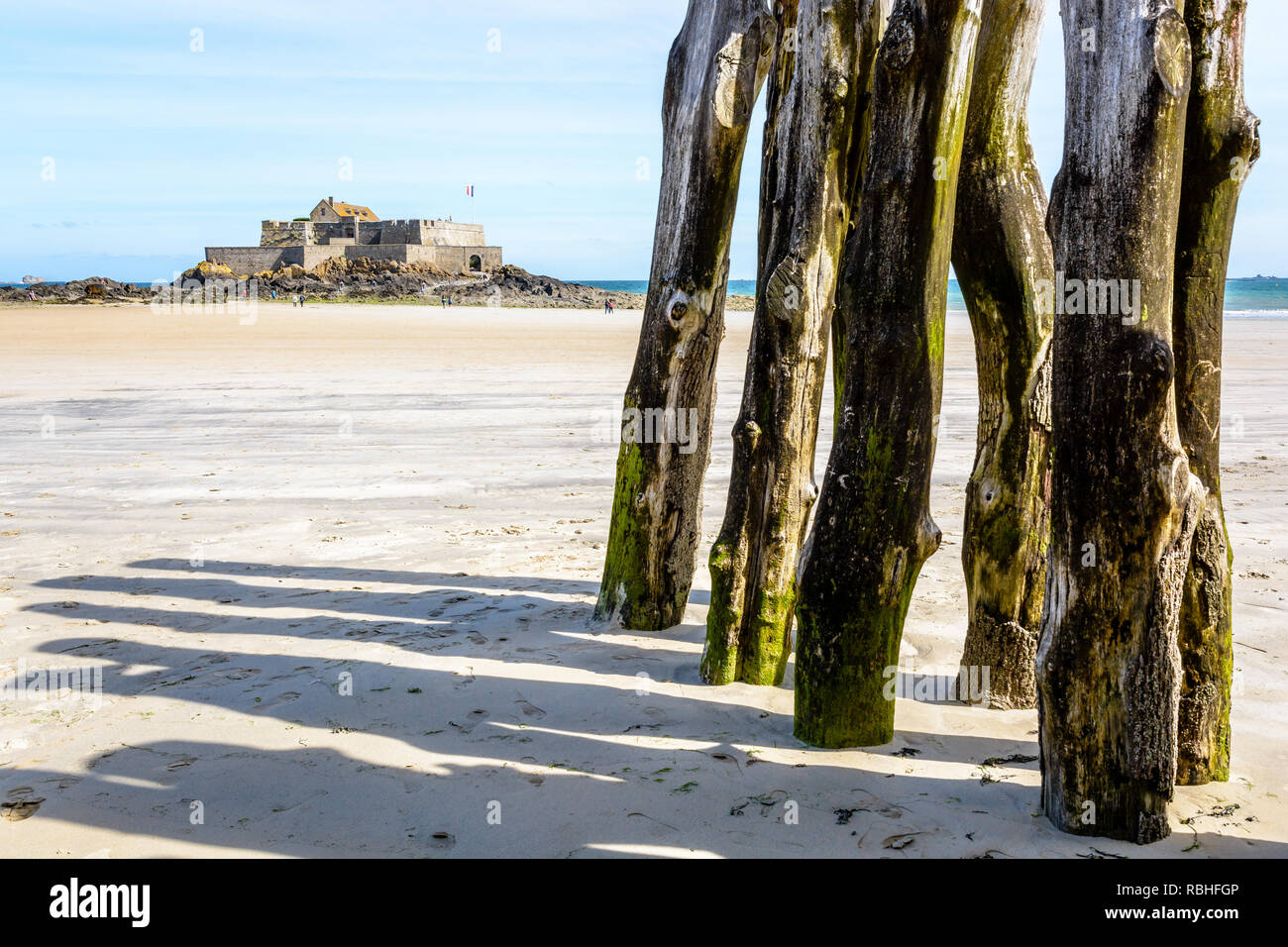 The Fort National, built off the coast of Saint-Malo in Brittany, seen from the beach at low tide with wooden breakwater posts in the foreground. Stock Photo