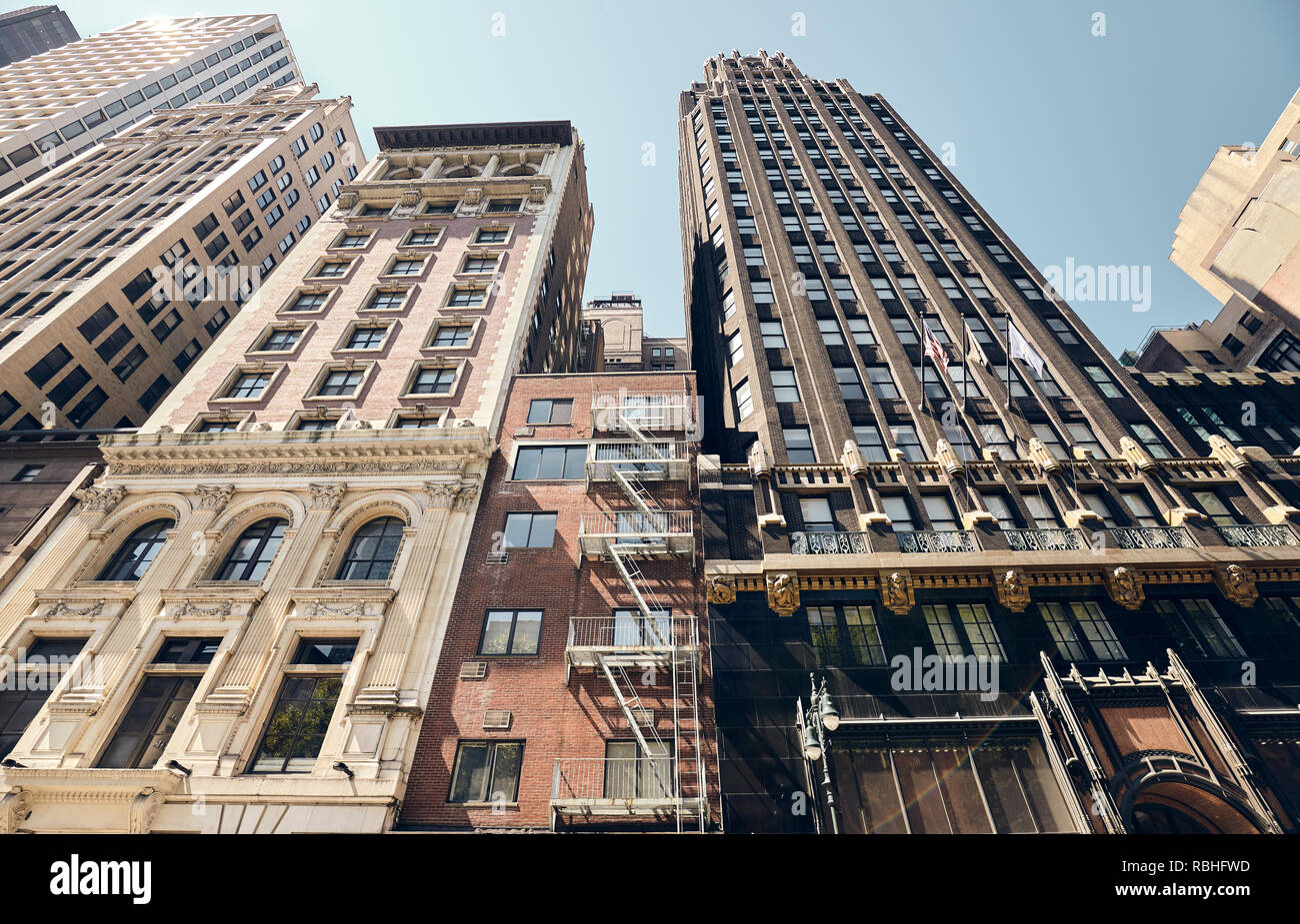Looking up at old New York buildings, color toned picture with a lens flare, USA. Stock Photo