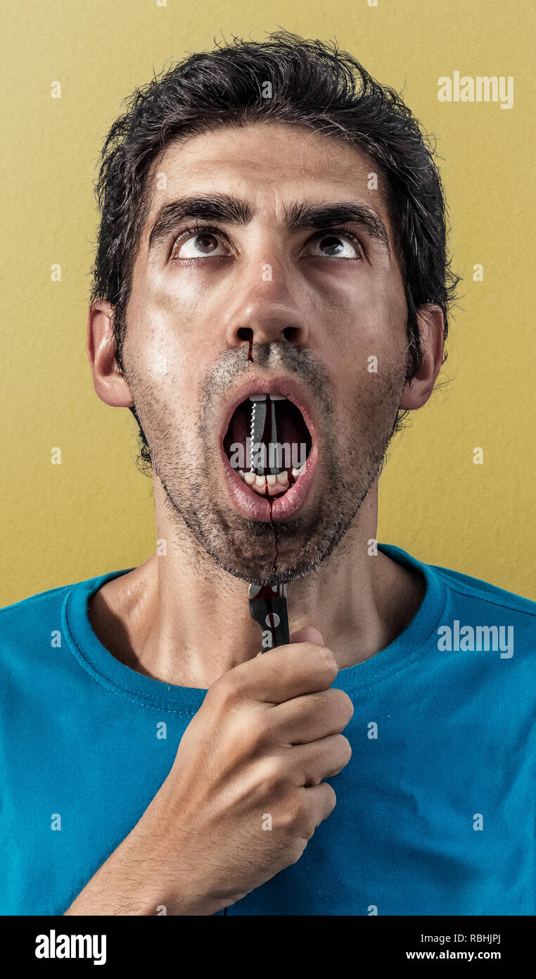A man stabbing himself with a kitchen knife under his chin. Stock Photo
