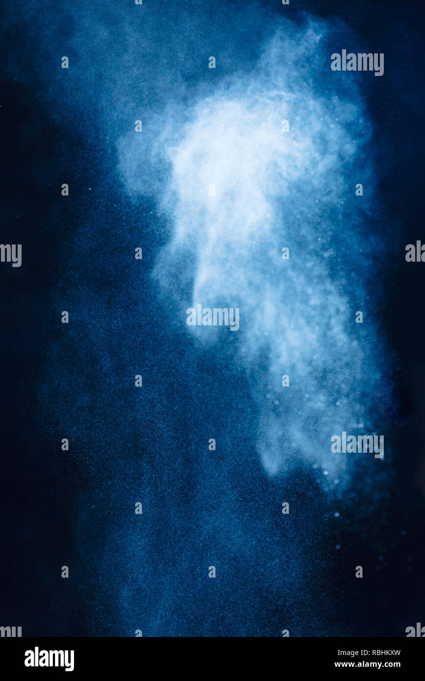Flour powder explosion in motion. Action food photography. Light blue dust on a black background