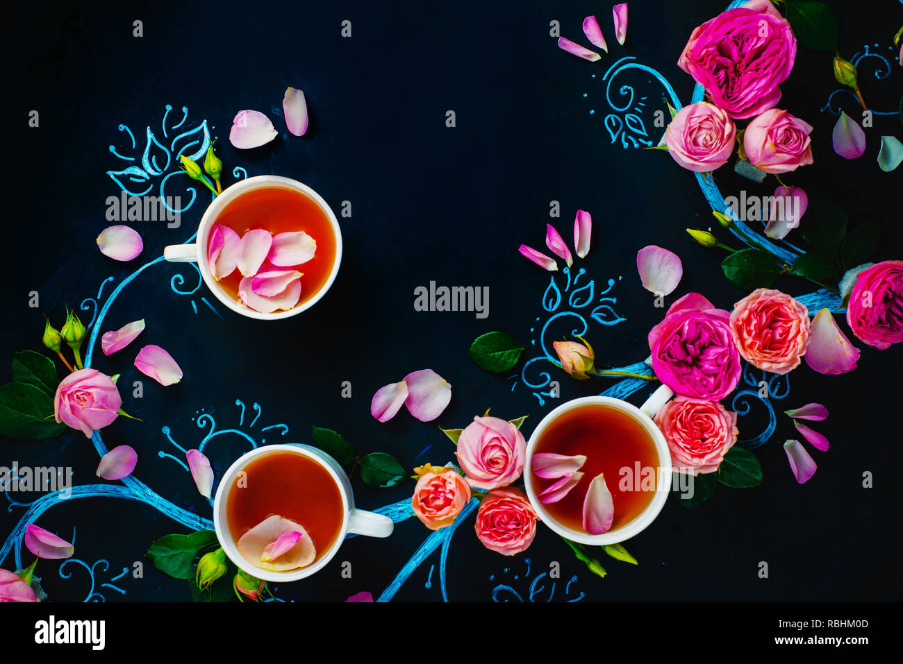 Teacups and flower petals in chalk tree flat lay. Rose tea creative flat lay on a dark background with copy space Stock Photo