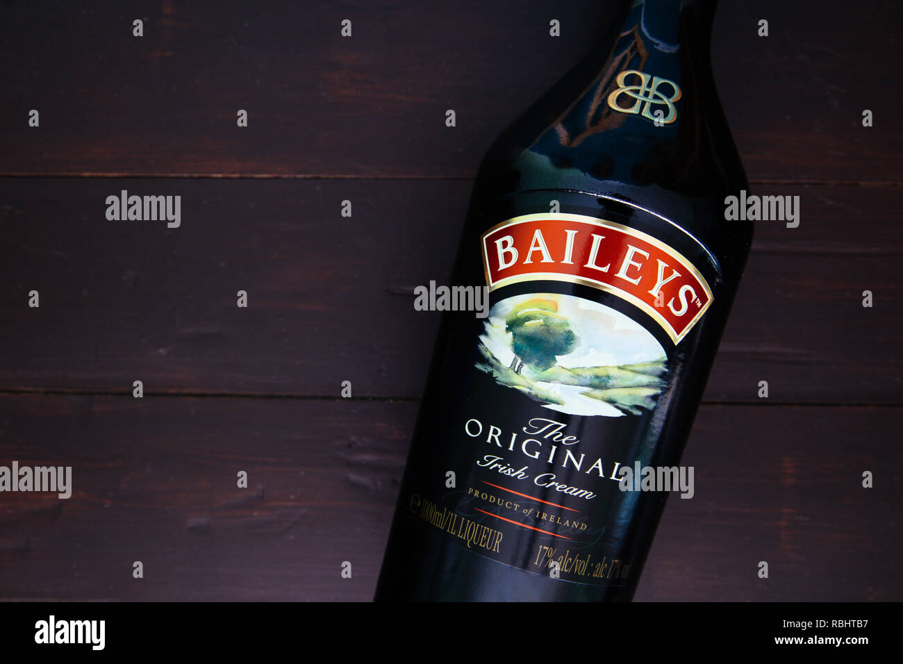 LONDON - JANUARY 08, 2019: Baileys Irish Cream glass bottle on dark wood background Stock Photo