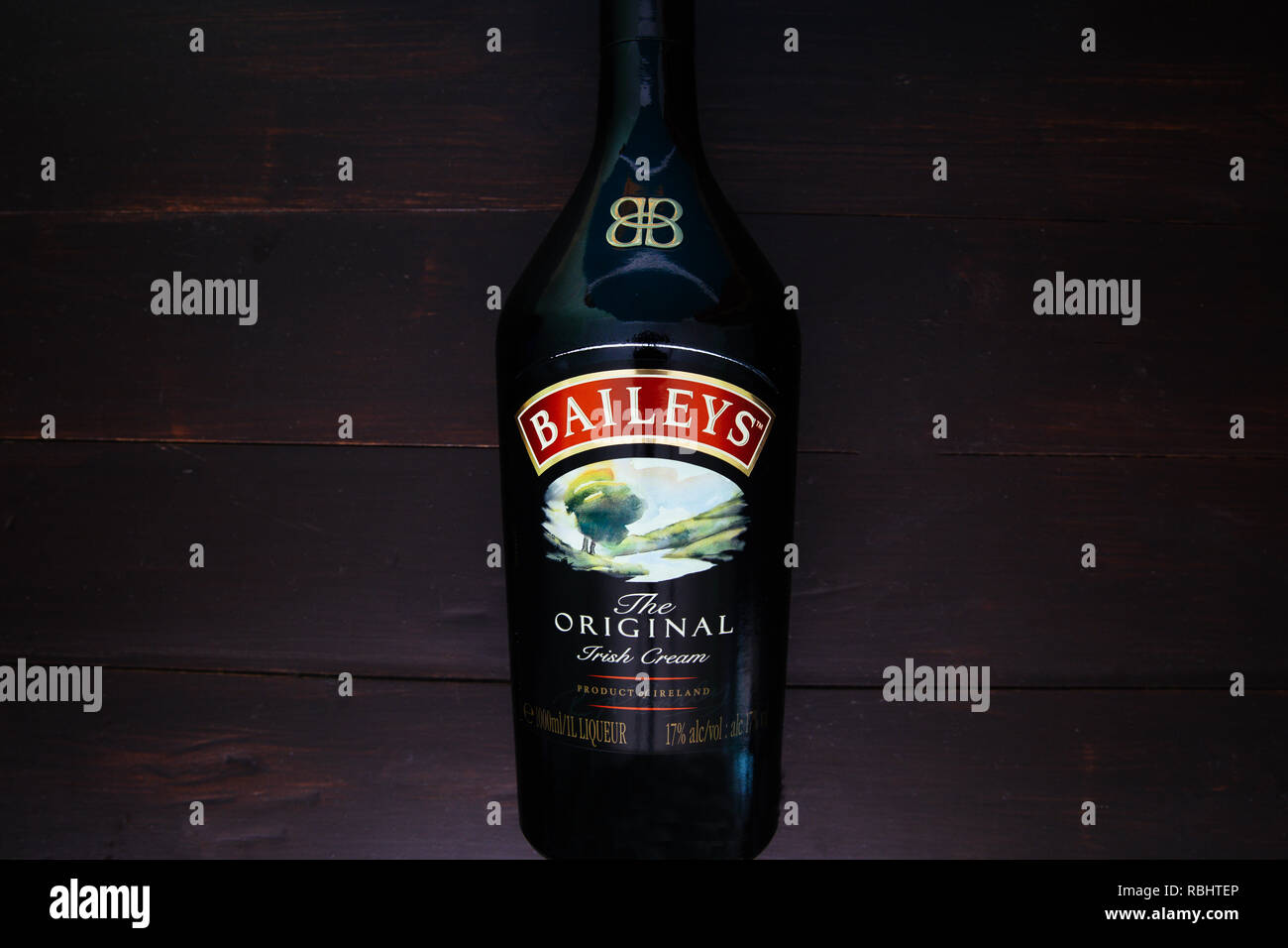 LONDON - JANUARY 08, 2019: Baileys Irish Cream glass bottle on dark wood background Stock Photo