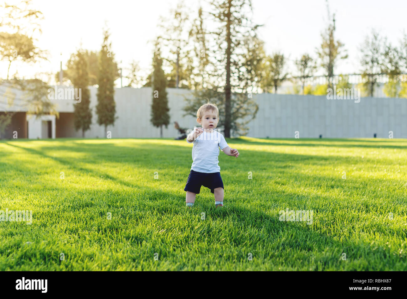 Cute baby runs on a green lawn playing catch-up in nature on a Sunny ...