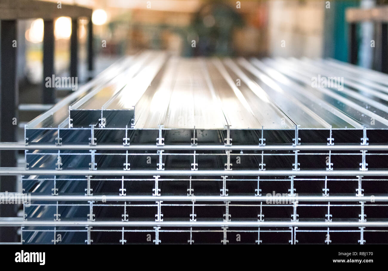 Aluminium profiles placed in a row inside an aluminum profile factory. Stock Photo