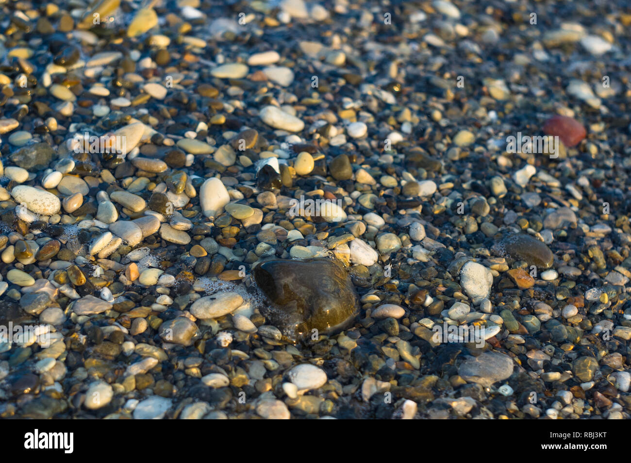 pebble stones on the sea beach on a warm summer day, the rolling waves ...
