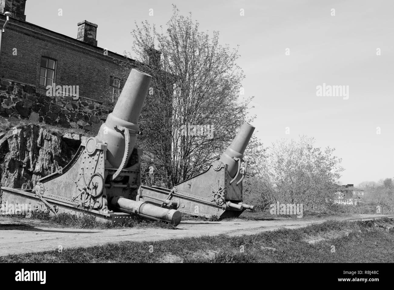 Two rusted cannons in front of a military building on Suomenlinna island, Finland. A total of 100 stand on the sea fortress - monochrome processing Stock Photo