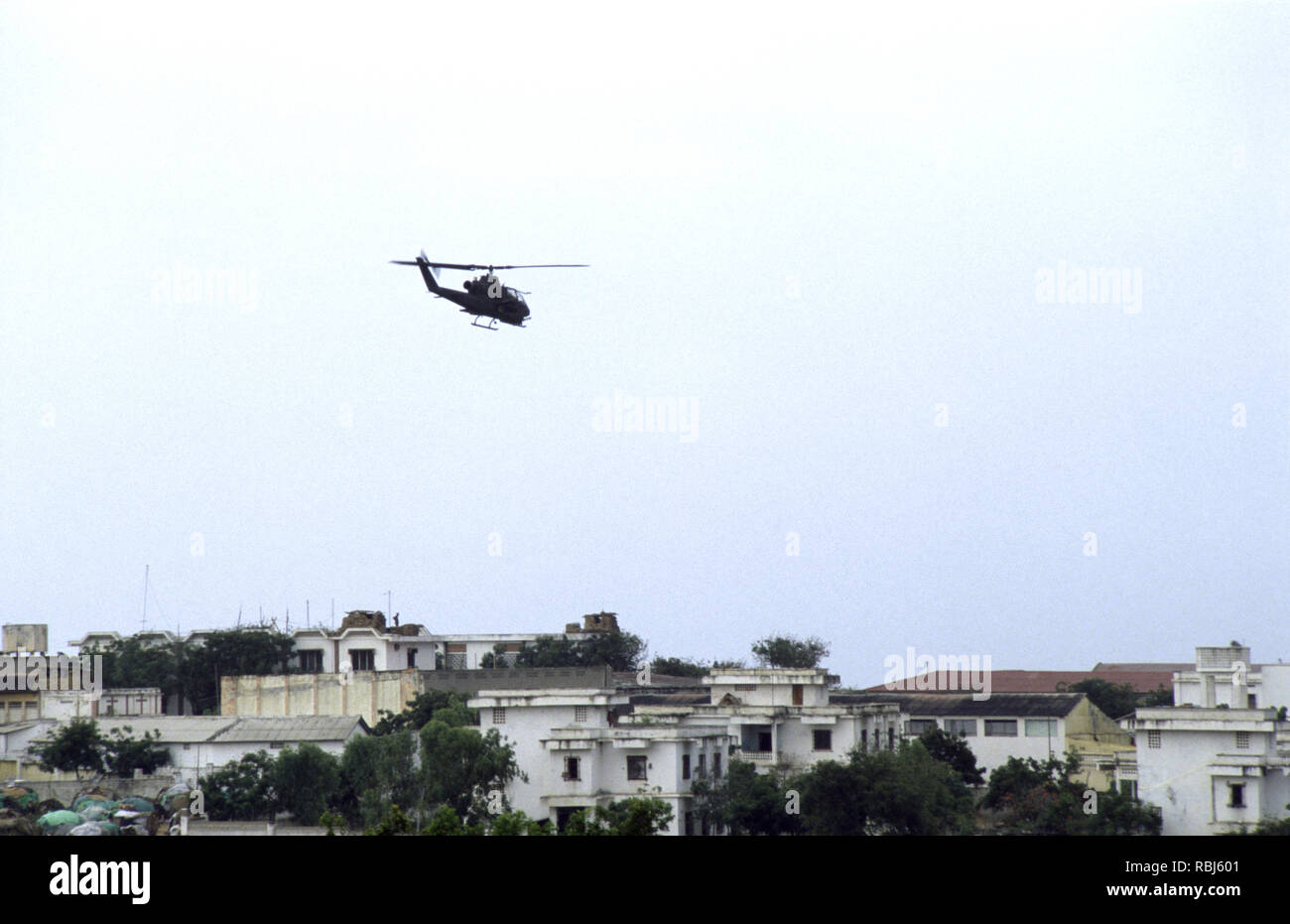 10th October 1993 A U.S. Army Bell AH-1 Cobra attack helicopter patrols low above the rooftops of Mogadishu, Somalia. Stock Photo