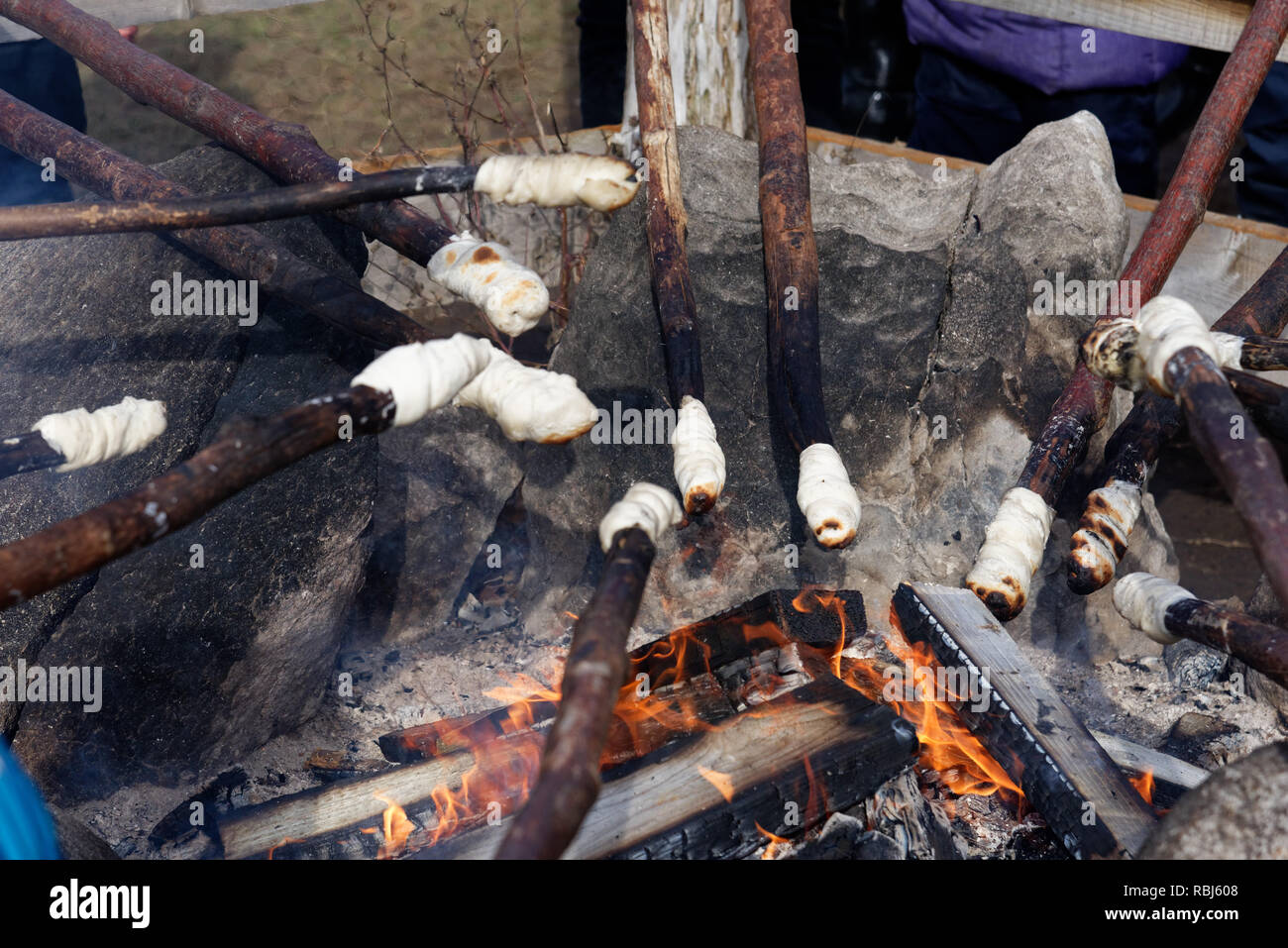 Cooking bannock campfire bread on sticks over an open fire Stock Photo