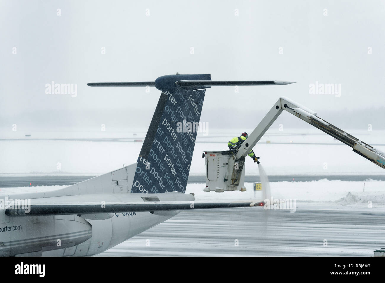An aiport employee spraying de-icer on an aircraft's wings in winter, getting the plane ready for departure. Quebec City Jean Lesage airport. Stock Photo