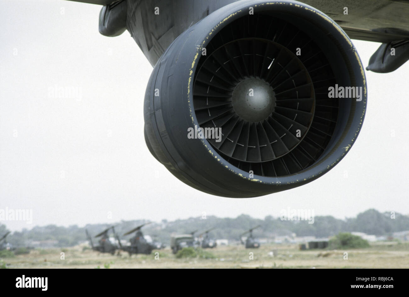 10th October 1993 One of the four big engines of a USAF Lockheed Galaxy C5 military transport jet of Air Mobility Command, parked at Mogadishu Airport in Somalia. In the background are Cobra attack helicopters and a medical Huey helicopter. Stock Photo