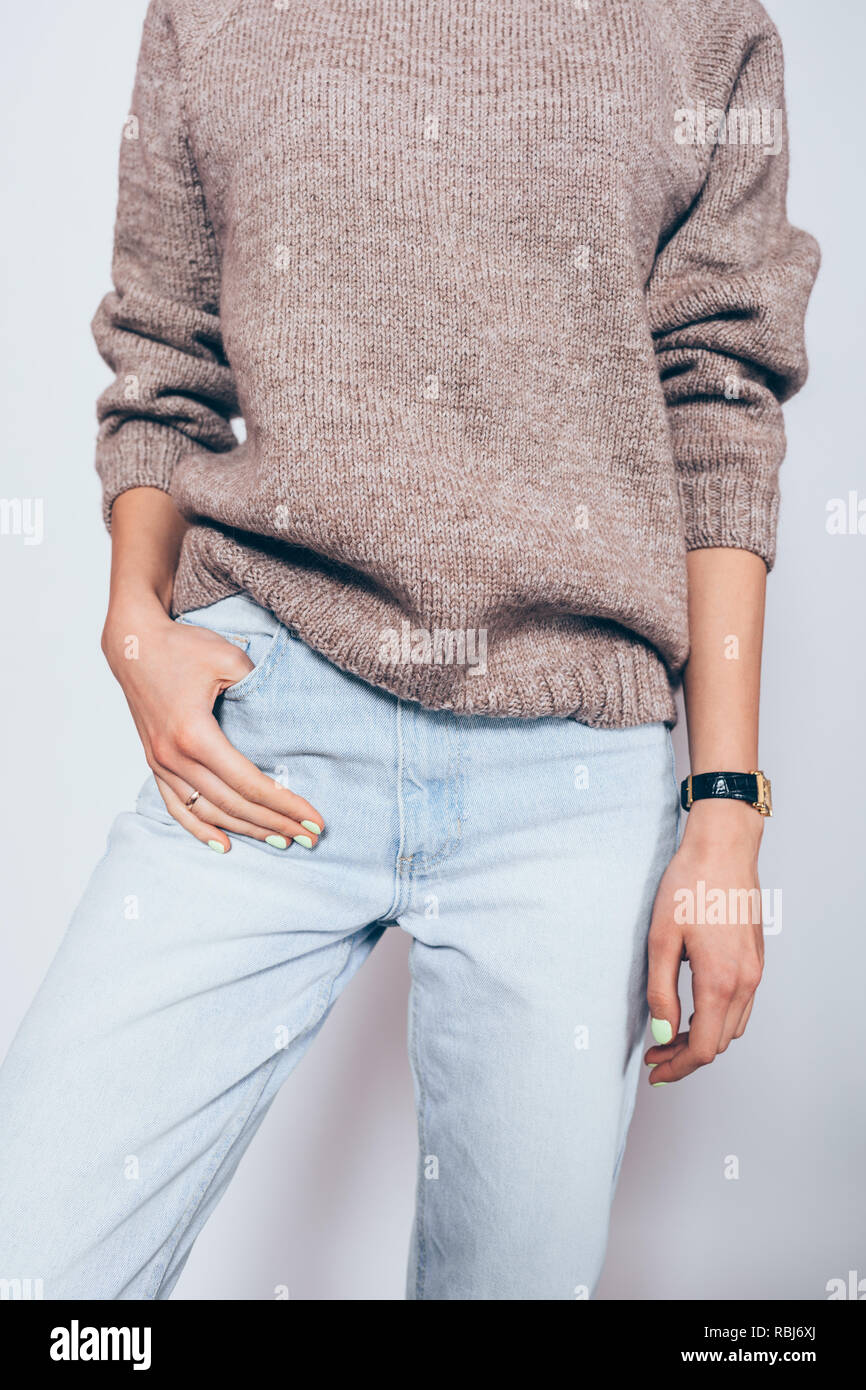 Young woman wearing plain oversized brown sweater and blue boyfriend jeans. Relaxed casual outfit for winter. Stock Photo