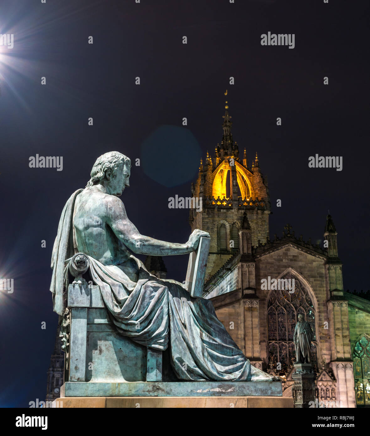 David Hume statue by Alexander Stoddart lit at night with St Giles Cathedral, Royal Mile, Edinburgh, Scotland, UK Stock Photo