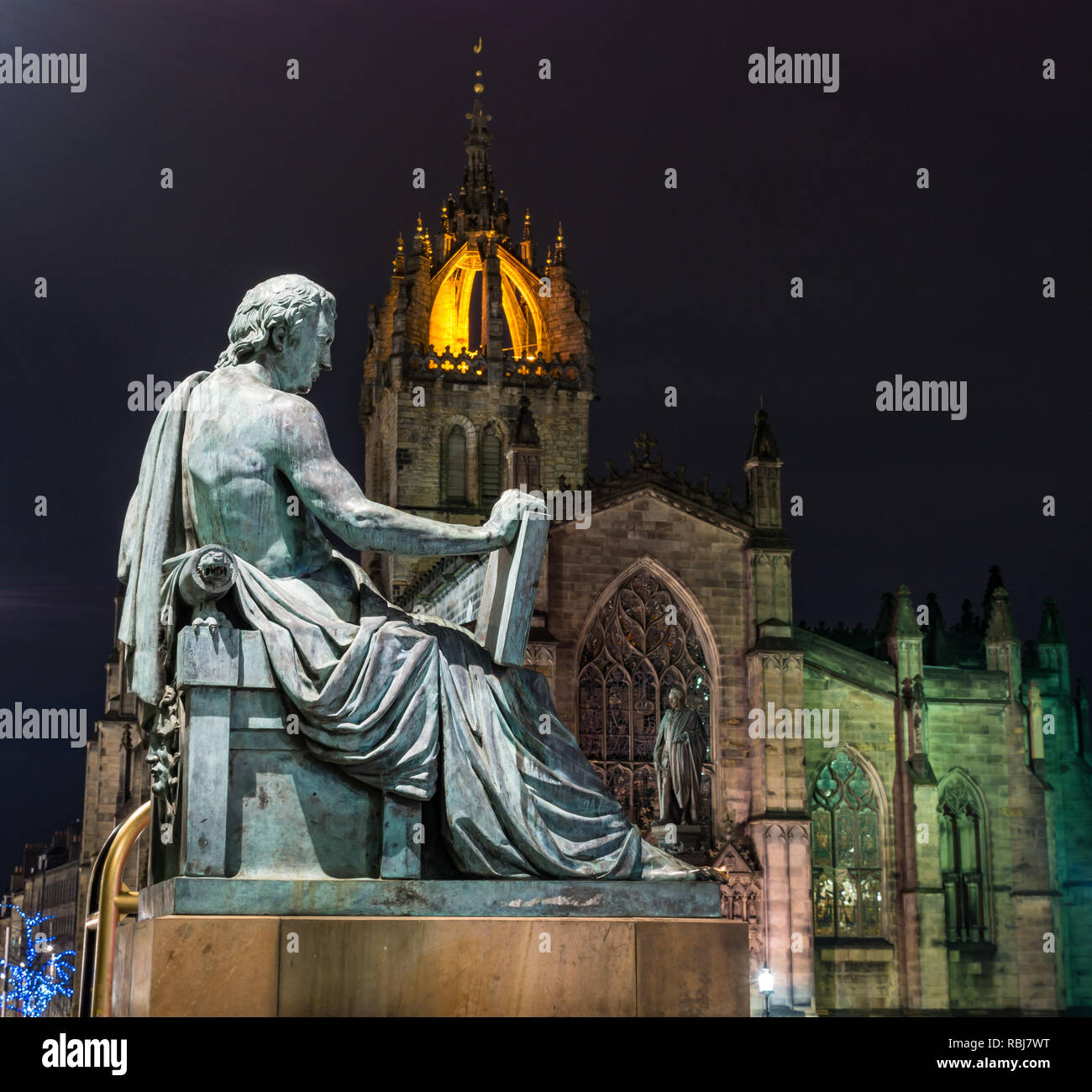 David Hume statue by Alexander Stoddart lit at night with St Giles Cathedral, Royal Mile, Edinburgh, Scotland, UK Stock Photo