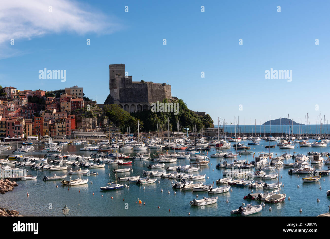 Boats anchored at harbour, with Lerici Castle and Gulf of La Spezia in the background, Lerici, Italy Stock Photo