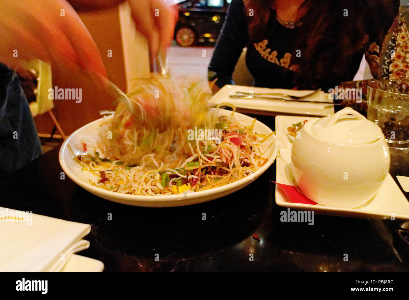 The hands of a waitress throwing a salad Stock Photo