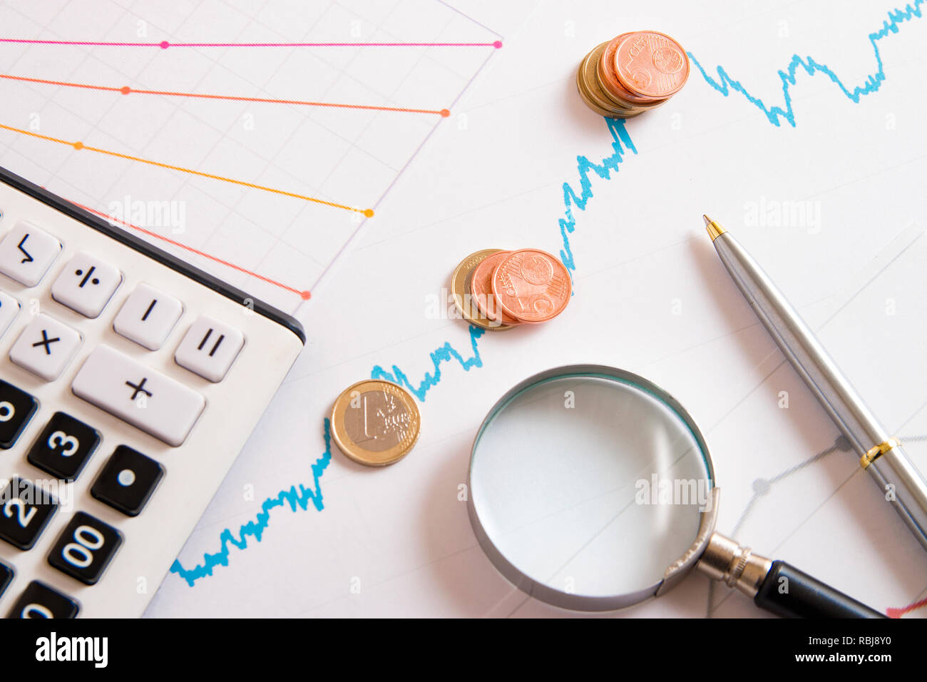 calculator and coins on the rising chart and magnifier Stock Photo Alamy