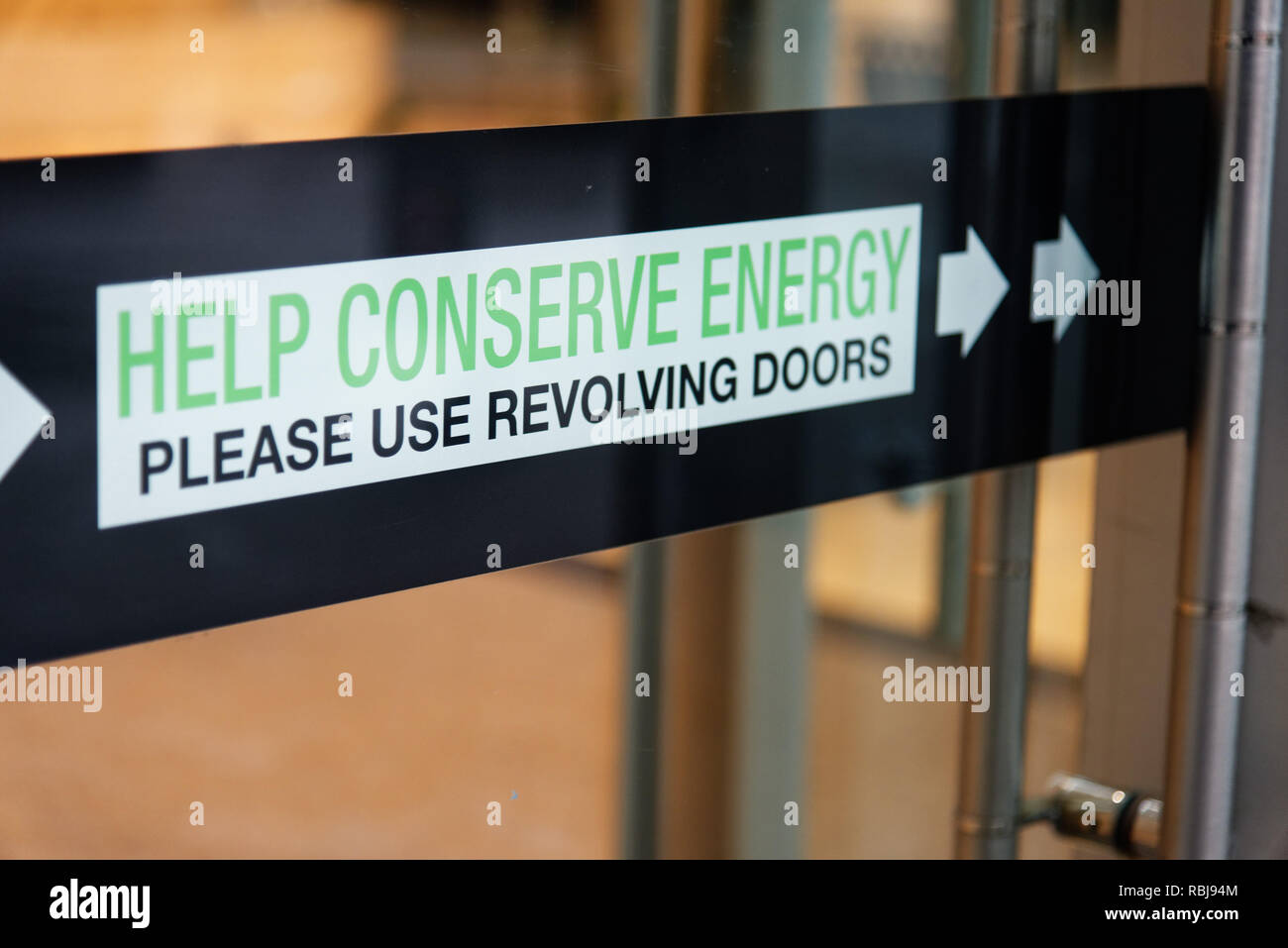 A sign in a Toronto building saying Help Conserve Energy - Please Use Revolving Doors Stock Photo