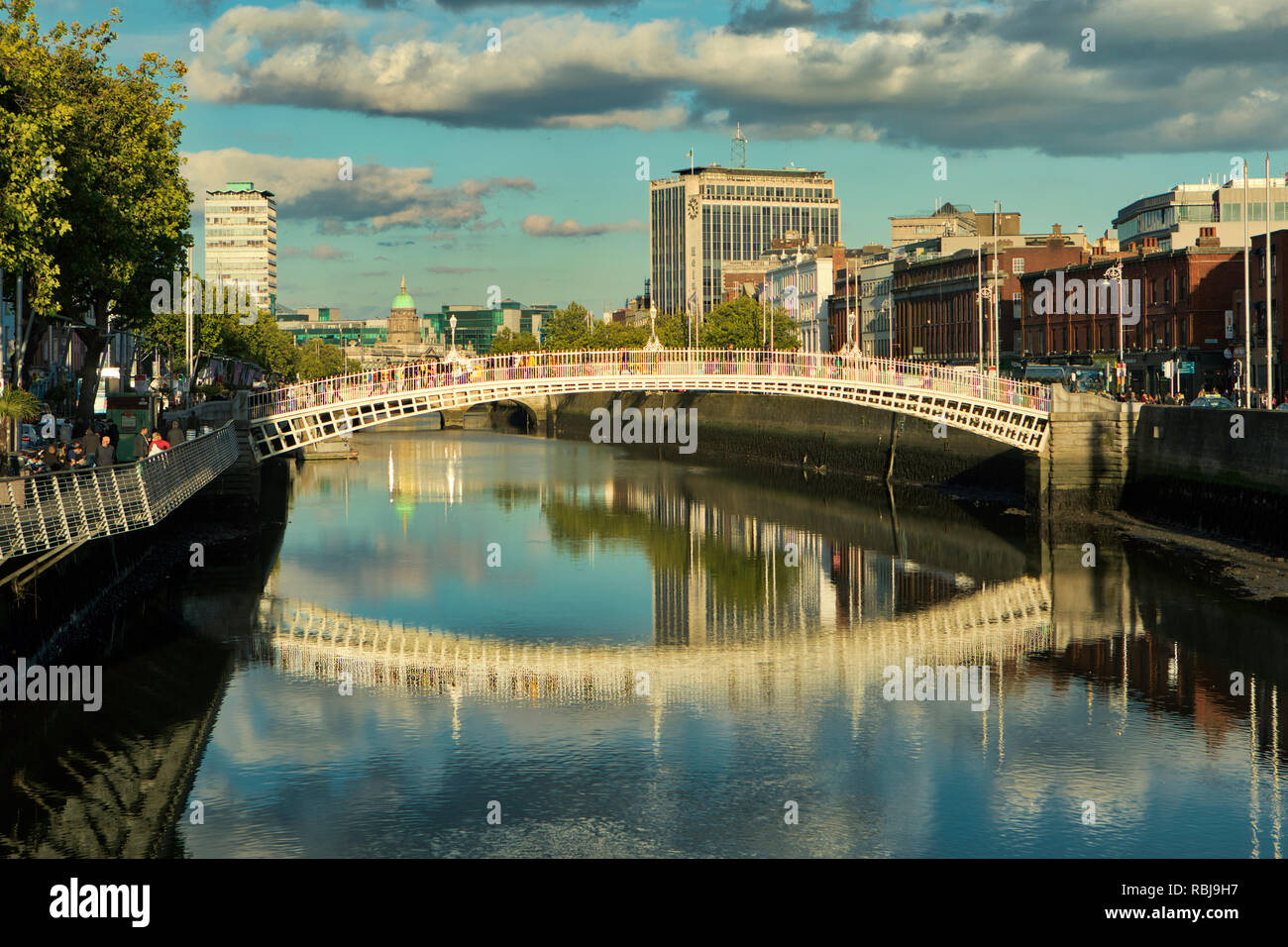 People walk over the Ha'penny Bridge over the Liffey River in Dublin ...