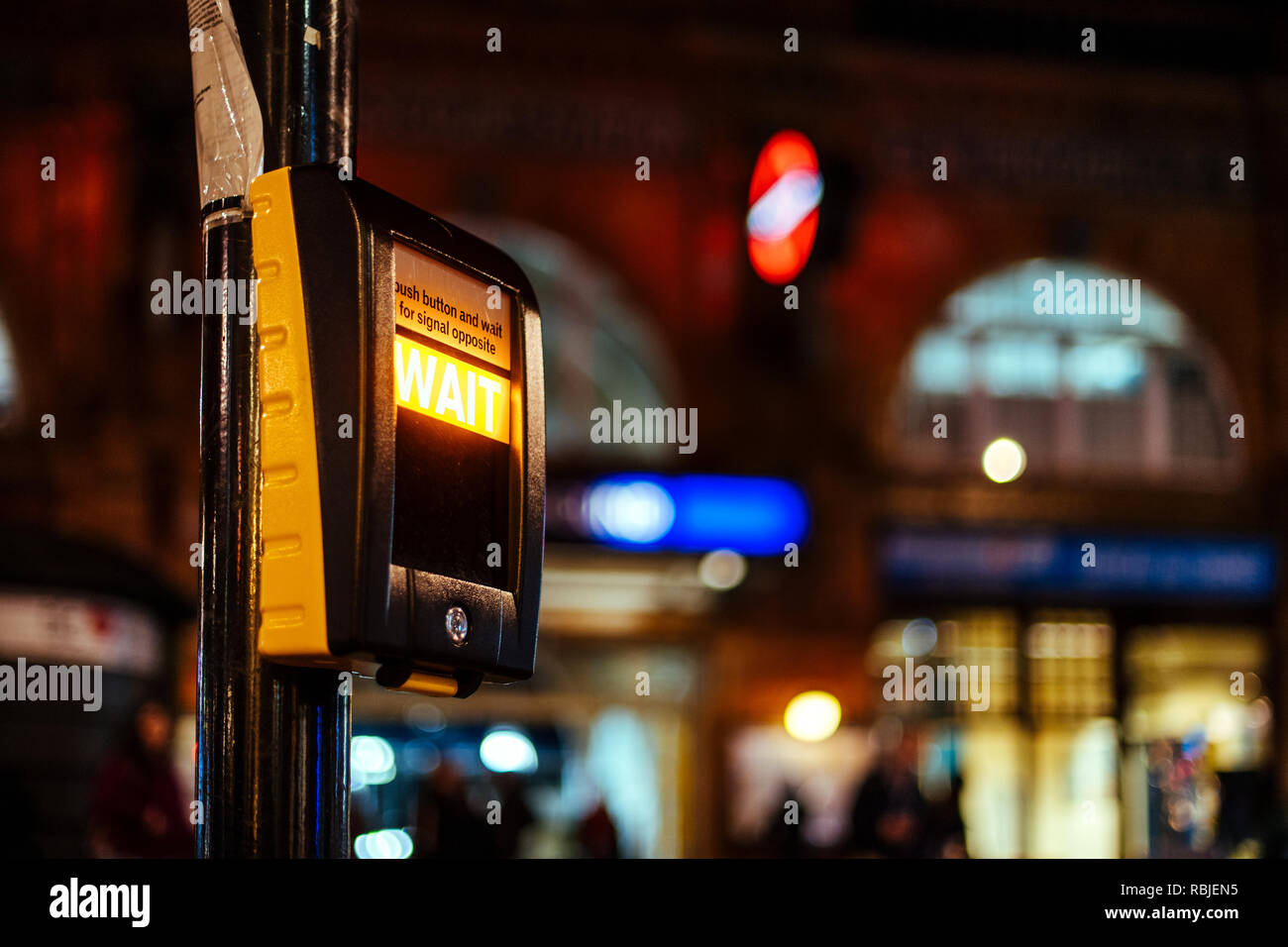 Push button and wait for siganl opposite sign on the rossing ligt street semaphore traffic light in central london, United Kingdom with defocused city in the background Stock Photo