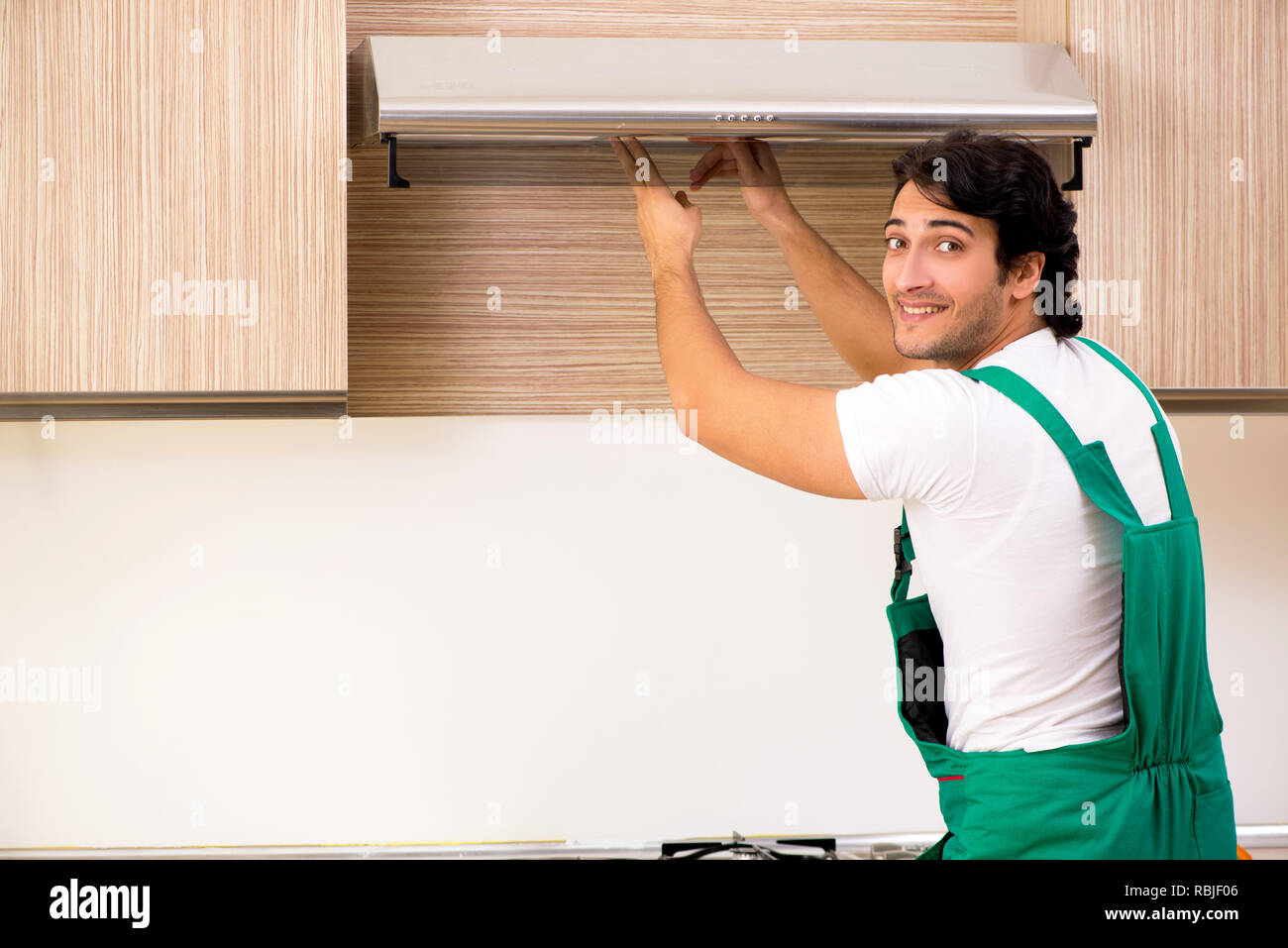 Young contractor repairing air-conditioner in kitchen Stock Photo