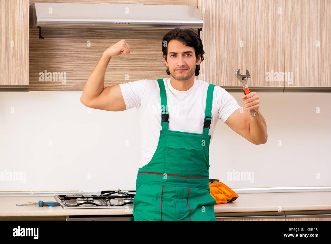 Young contractor repairing oven in kitchen Stock Photo