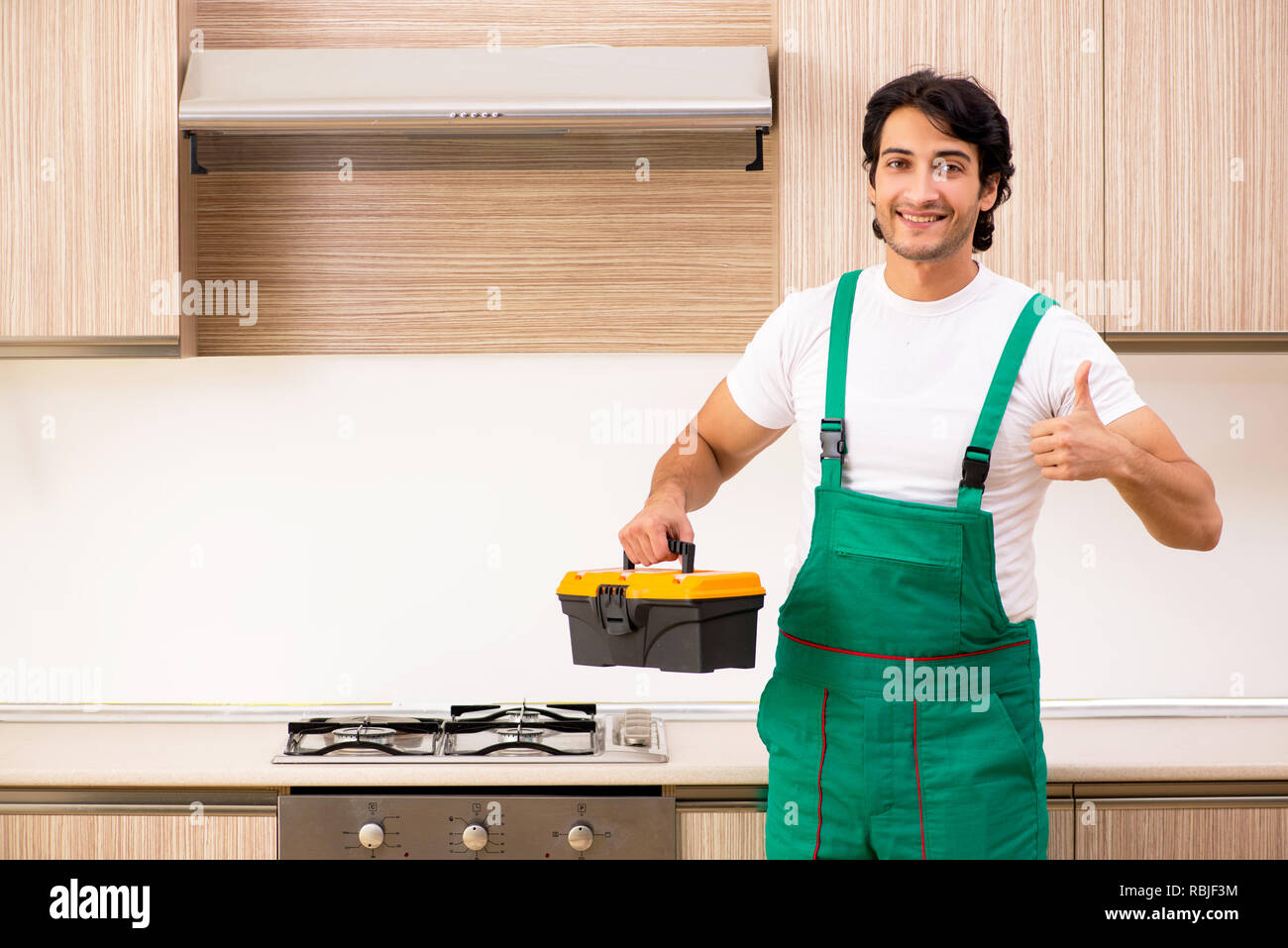 Young contractor repairing oven in kitchen Stock Photo