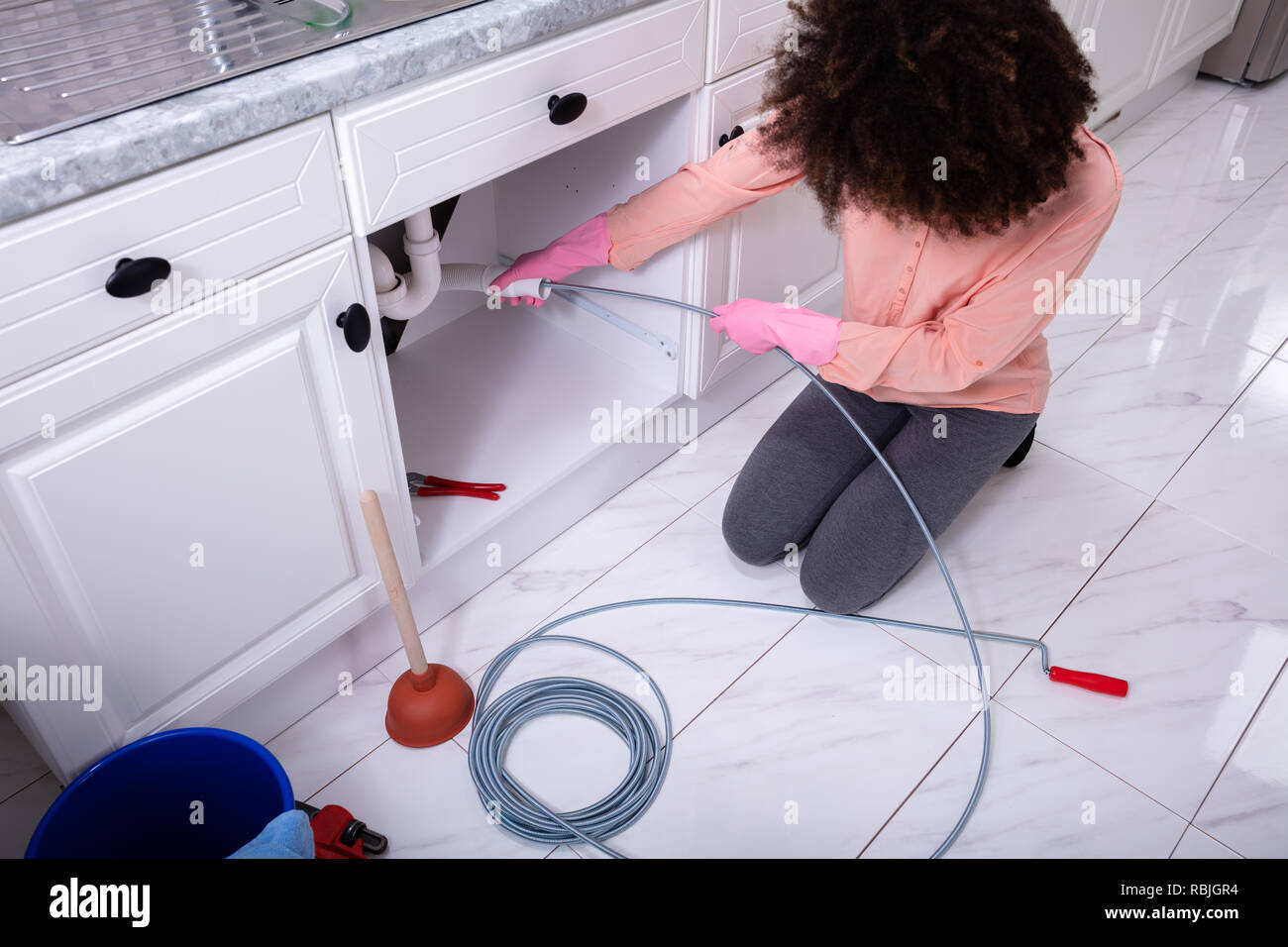 A Young Woman Cleaning Clogged Sink Pipe With Drained Cable In The Kitchen Stock Photo Alamy