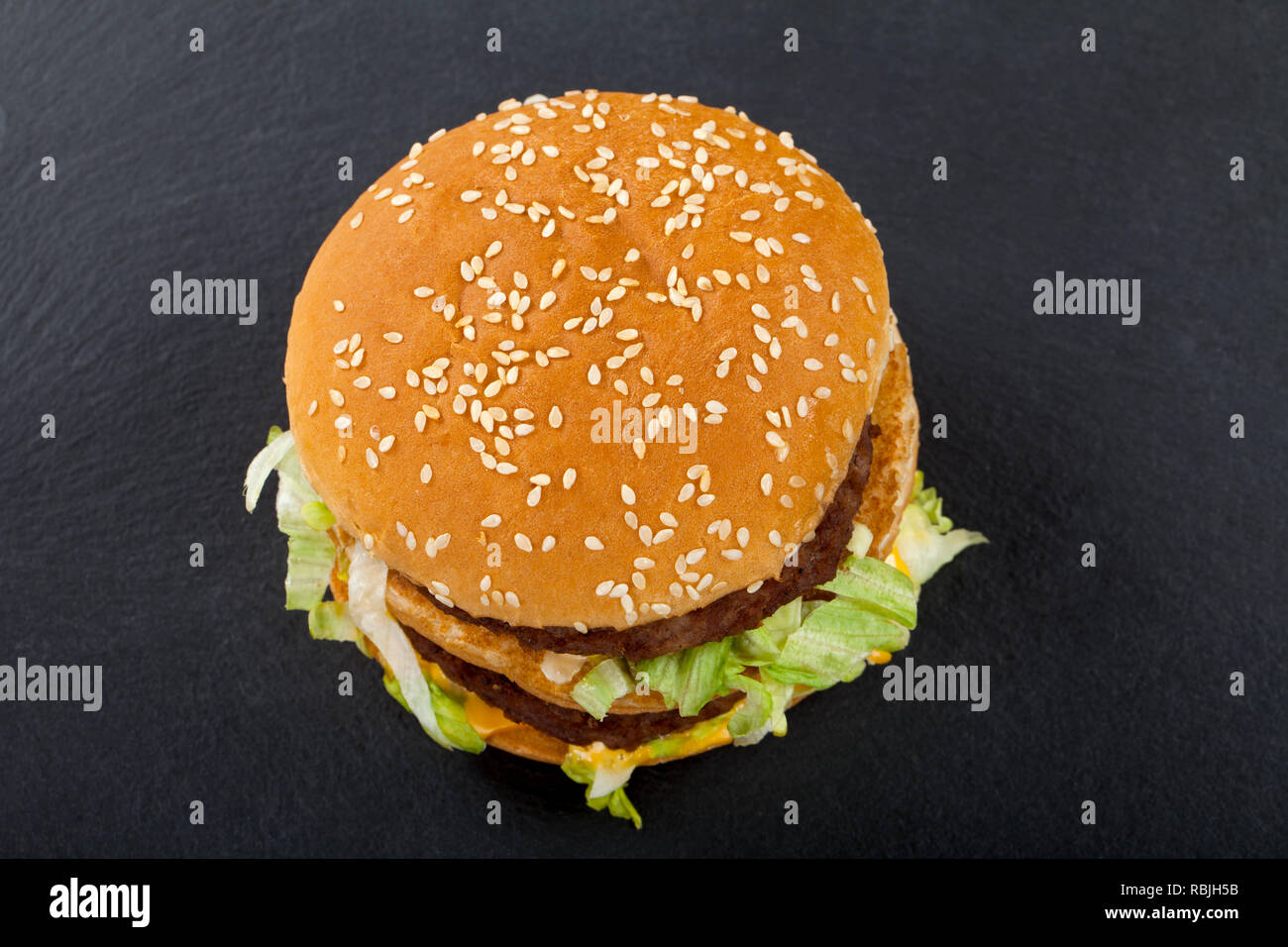 Picture of a delicious fresh double cheeseburger with sesame bun. Top view. Black background Stock Photo