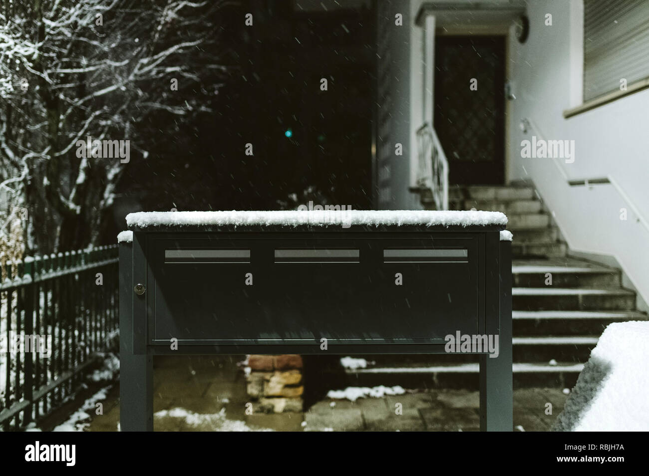 Postal boxes in front of the house - snowing calmly on a cold winter night  Stock Photo