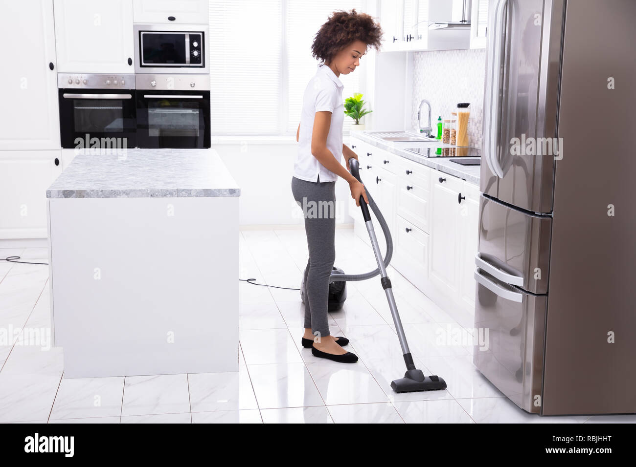 Close Up Of A Young Woman Cleaning The White Kitchen Floor With