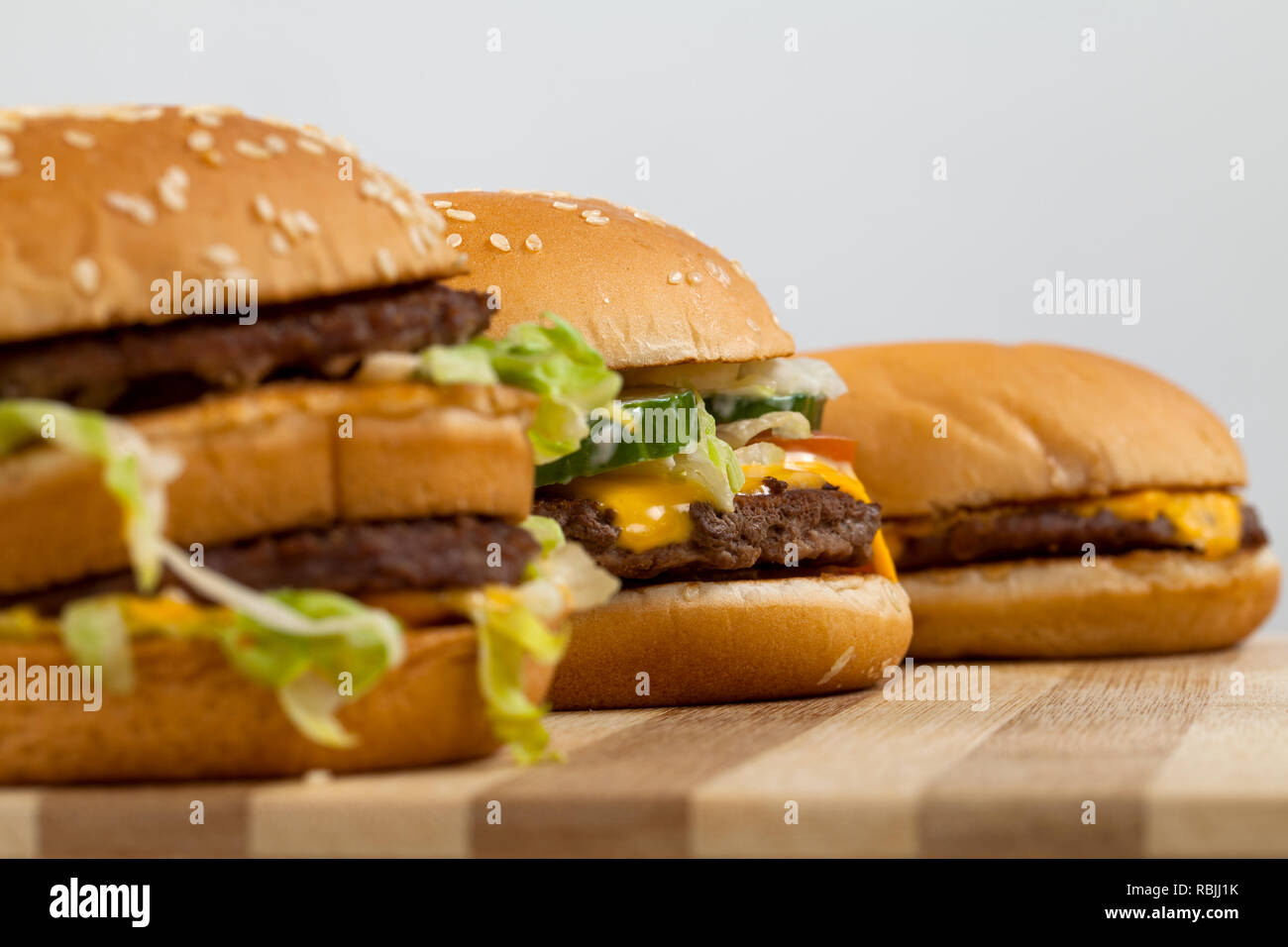 Three different type and size of delicious burgers on a wooden board ...