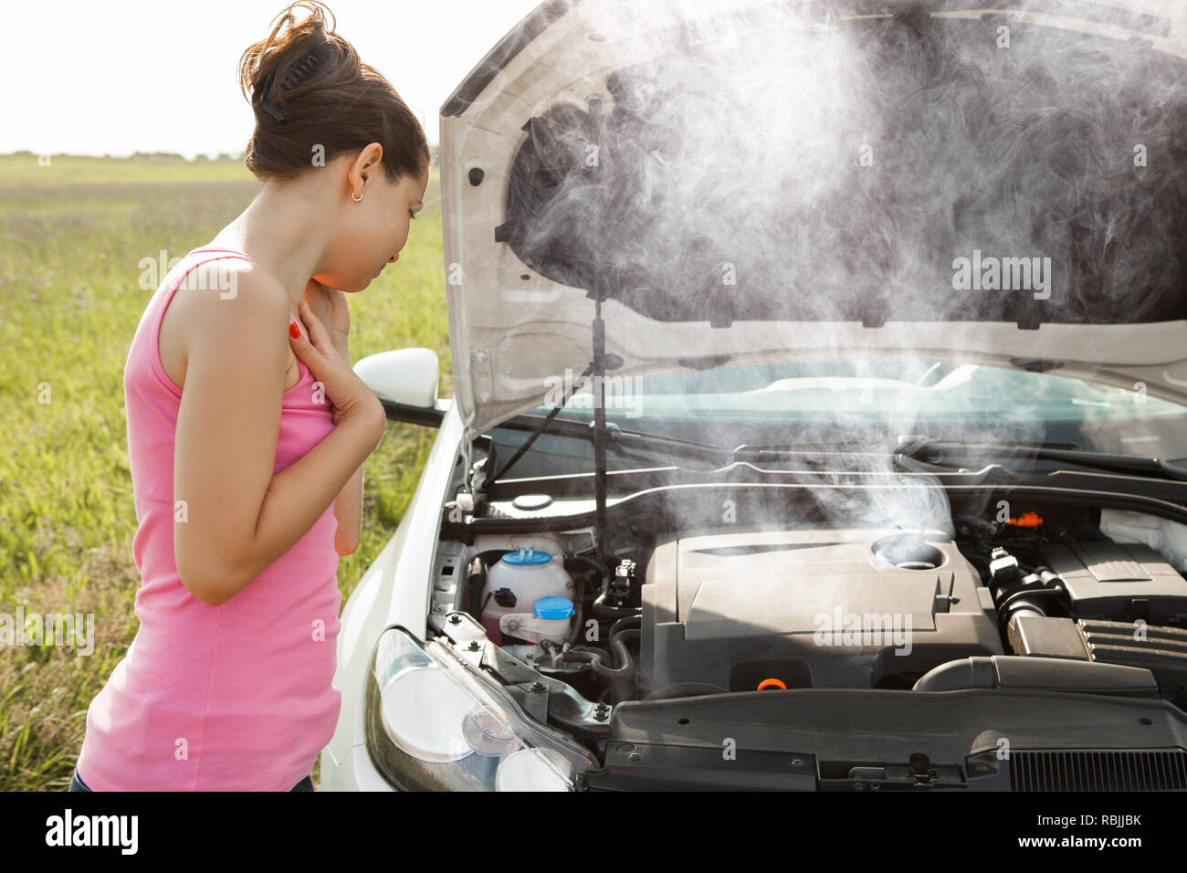 Side View Of A Sad Young Woman Looking At Broken Down Car Engine Stock Photo