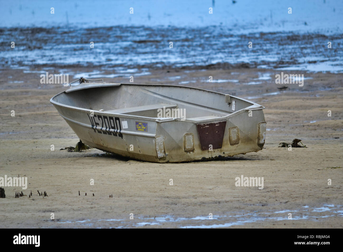 anchored small boat beached at low tide Stock Photo